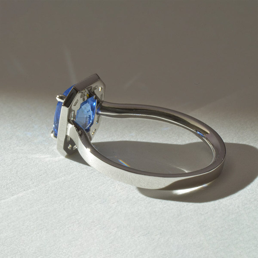 Cushion cut cornflower blue sapphire, with a halo of trazpezoid diamonds in platinum - view of under ring