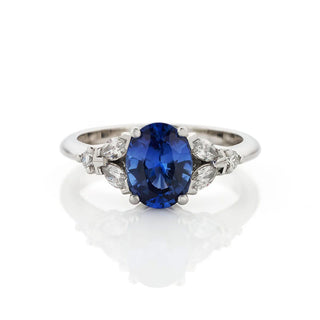 Platinum ring with a blue gemstone and diamond accents on a white background