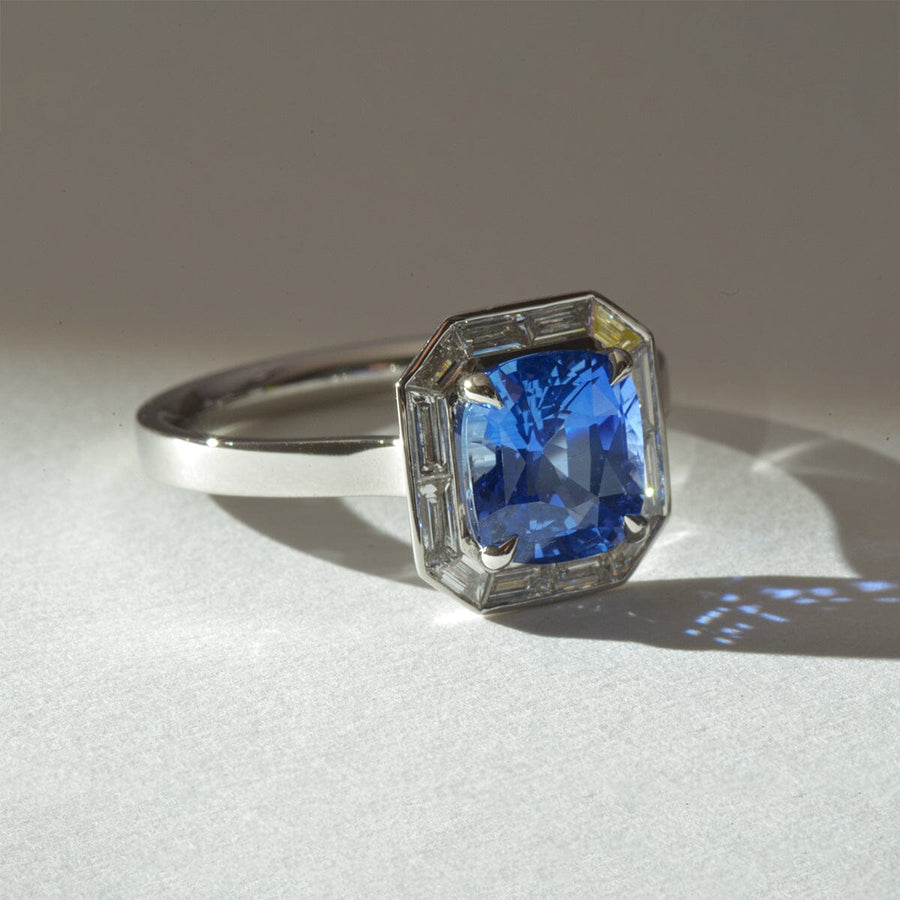Cushion cut cornflower blue sapphire, with a halo of trazpezoid diamonds in platinum