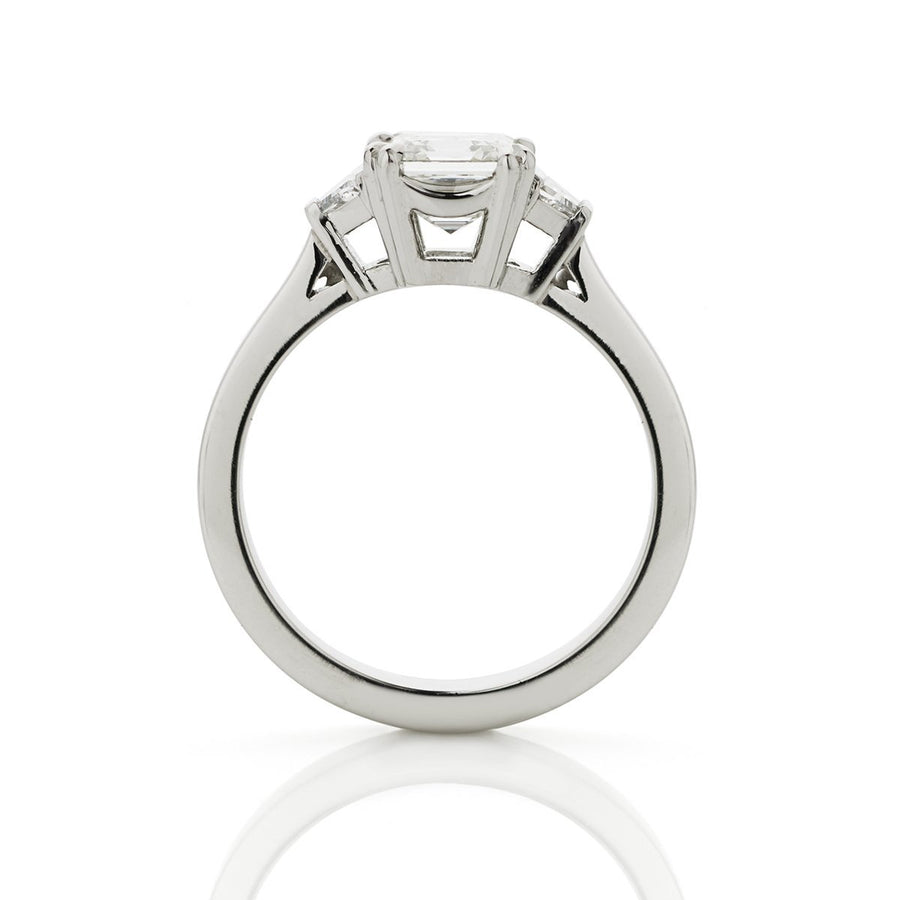 Side view of platinum three stone engagement ring, with an asscher cut diamond centre and trapezoid sides.