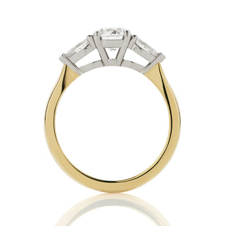 Side view of round and pear three stone engagement ring. Platinum double bezel settings, with up-swept 18ct yellow gold band.