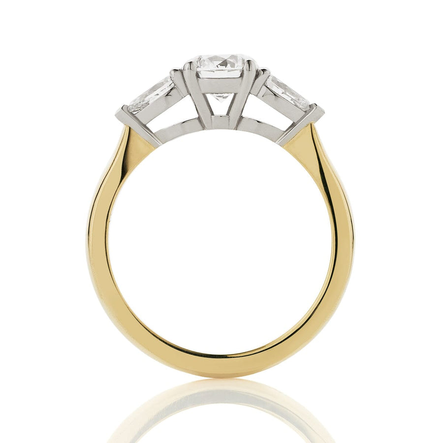 Side view of round and pear three stone engagement ring. Platinum double bezel settings, with up-swept 18ct yellow gold band.